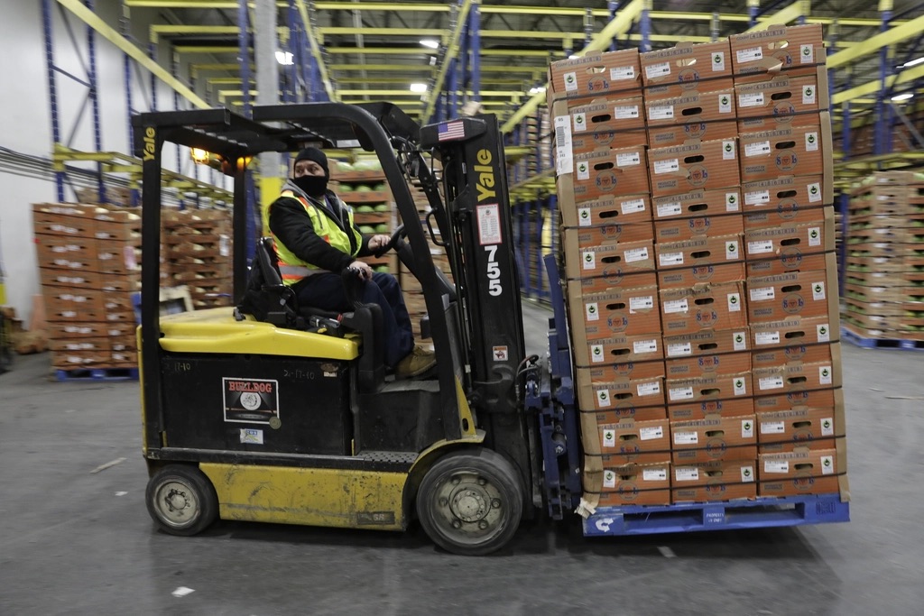 Forklift moving a loaded pallet through warehouse racking